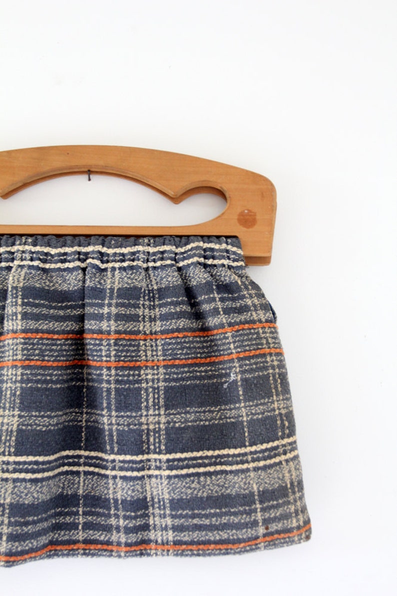 May include: A vintage wooden framed handbag with a plaid fabric lining in shades of blue, white, and orange.