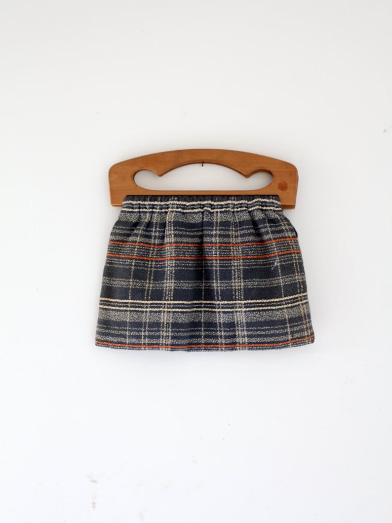 May include: A plaid fabric bag with a wooden handle. The bag is blue, white, and orange.