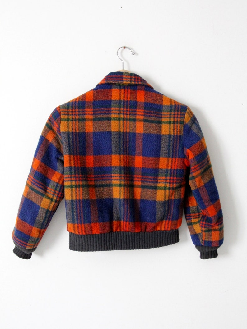 May include: A blue, orange, and green plaid bomber jacket with a ribbed knit collar, cuffs, and waistband.
