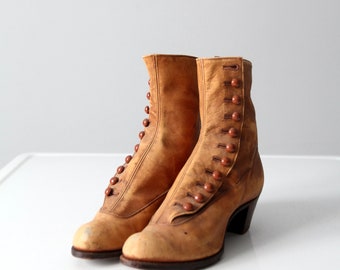 May include: A pair of brown leather ankle boots with button fastenings. The boots have a worn look and are slightly distressed.