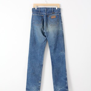 K&ouml;nnte beinhalten: Eine blaue Jeanshose mit einem braunen Leder-Patch auf der Ges&auml;&szlig;tasche.