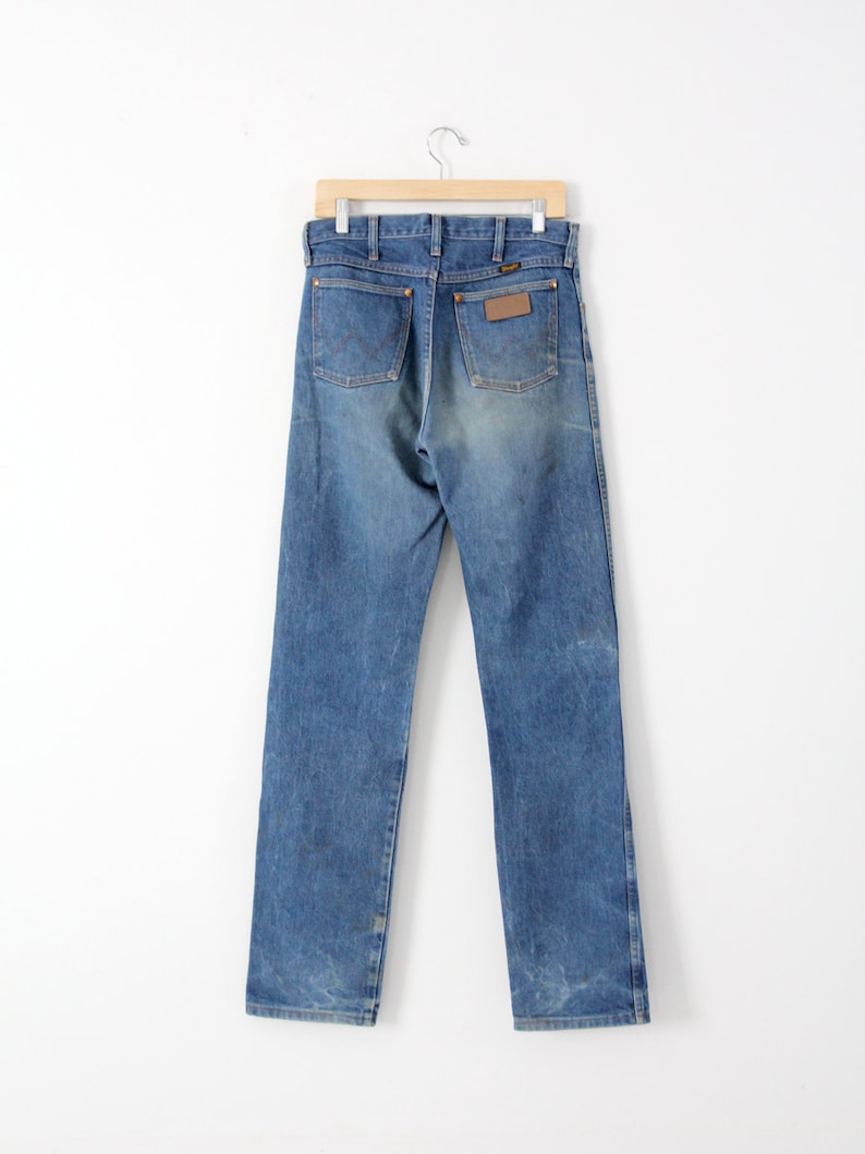 K&ouml;nnte beinhalten: Eine blaue Jeanshose mit einem braunen Leder-Patch auf der Ges&auml;&szlig;tasche.