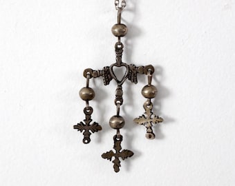 May include: A silver necklace with a pendant featuring a heart and four small crosses hanging from it.