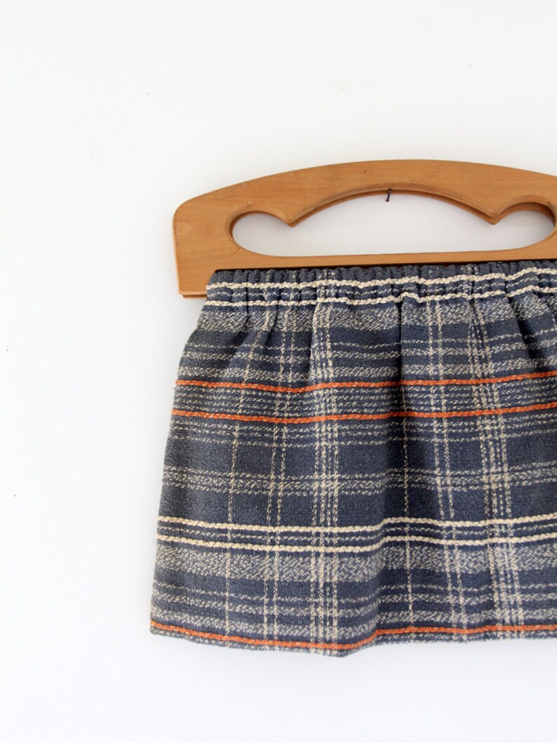 May include: A vintage plaid fabric tote bag with a wooden handle. The bag is blue, white, and orange plaid.