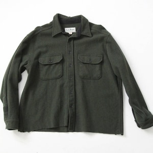 Peut inclure: Une chemise en flanelle à manches longues de couleur vert foncé avec un devant boutonné et deux grandes poches. La chemise porte une étiquette "L.L.Bean" sur le devant.