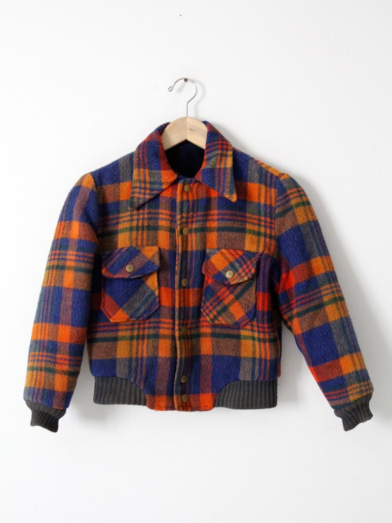 May include: A blue, orange, and brown plaid jacket with a button-up front and two large pockets. The jacket has a ribbed knit collar and cuffs.