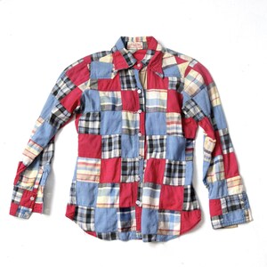 May include: A long-sleeved patchwork shirt with a button-up front. The shirt is made of different plaid fabrics in shades of red, blue, and yellow.