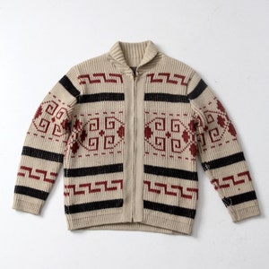 Puede incluir: Un cárdigan beige con cremallera y un patrón geométrico en negro, rojo y blanco.