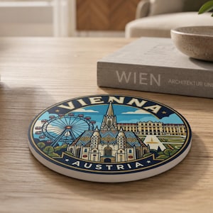 Könnte beinhalten: Ein runder Keramikuntersetzer mit einer farbenfrohen grafischen Illustration von Wien, Österreich. Das Design zeigt das Riesenrad, den Stephansdom und das Schloss Belvedere, mit dem aufgedruckten Text VIENNA und AUSTRIA in Fettschrift.