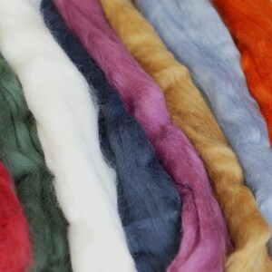 May include: A collection of eight strands of wool yarn in various colours, including red, green, white, blue, pink, gold, light blue, and orange.