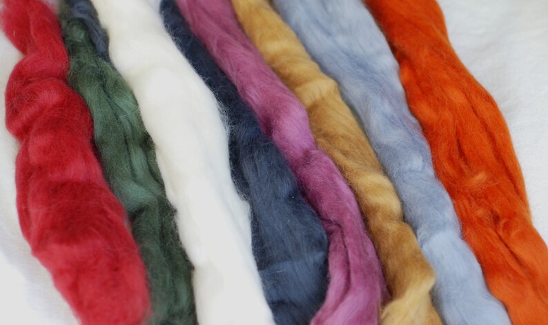 May include: A collection of eight strands of wool yarn in various colours, including red, green, white, blue, pink, gold, light blue, and orange.