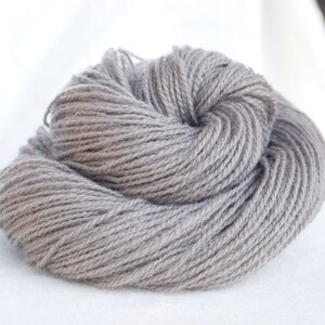 Puede incluir: Un ovillo de hilo gris, perfecto para tejer o hacer ganchillo.
