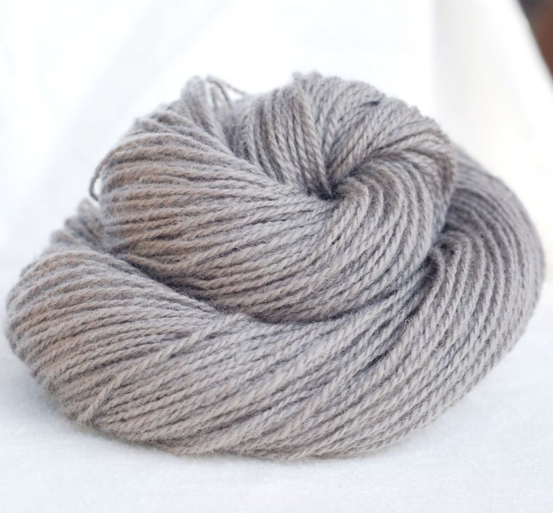 Puede incluir: Un ovillo de hilo gris, perfecto para tejer o hacer ganchillo.