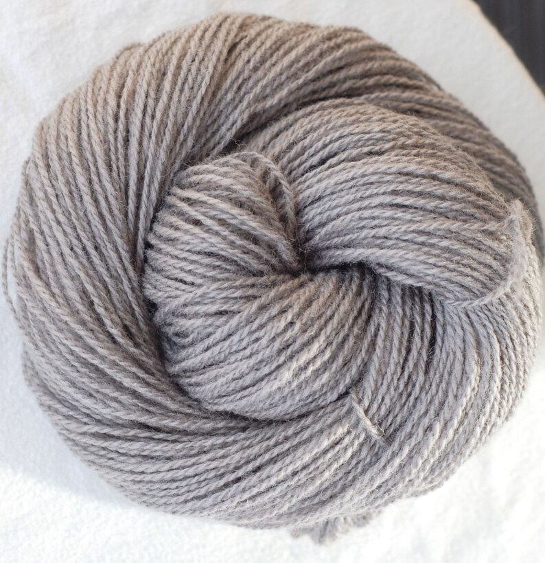 Puede incluir: Un ovillo de hilo gris, perfecto para tejer o hacer ganchillo.