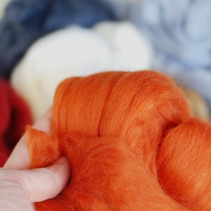 May include: A close-up of a bright orange wool roving, a type of fibre used for felting and spinning.