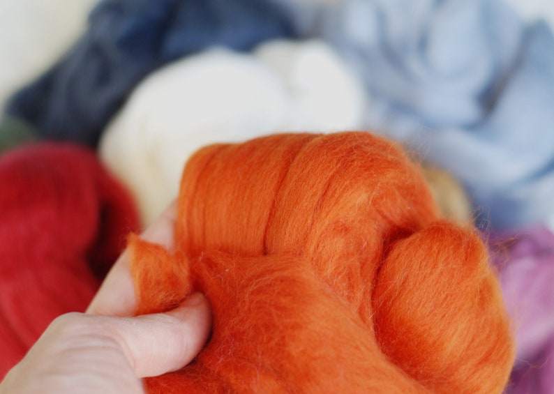 May include: A close-up of a bright orange wool roving, a type of fibre used for felting and spinning.
