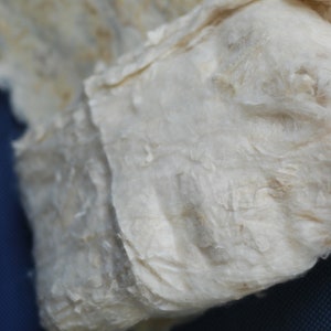 May include: Close-up of a white, fluffy, and textured material. The material is folded and appears to be made of natural fibers.