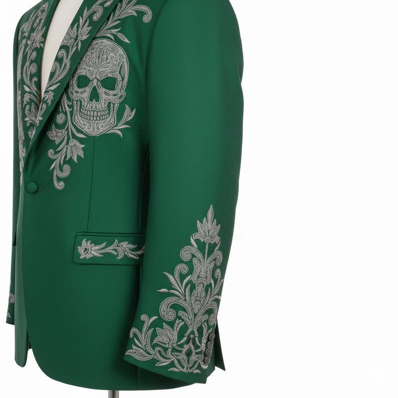May include: A green blazer with detailed silver embroidery, including a skull motif on the chest and floral patterns. The jacket has a single-button closure and is tailored. The design is intricate and eye-catching, with a unique and detailed aesthetic.