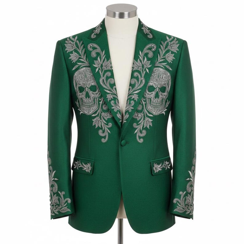 May include: A green blazer with silver skull and floral embroidery. The jacket has detailed embroidery on the lapels, shoulders, and sleeves. The blazer is displayed on a mannequin, showcasing its tailored fit and design.