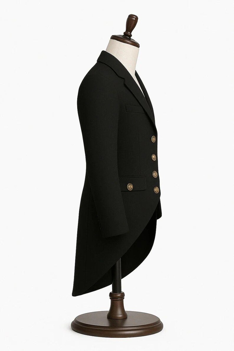 May include: A black tailcoat with gold-colored buttons, displayed on a mannequin. The formal jacket has a long, split tail and a classic, tailored design. The coat is made of a dark, possibly wool, fabric.
