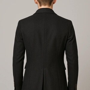 May include: A dark charcoal gray overcoat with a tailored fit. The back view shows a classic design with a notched lapel, two side pockets, and buttoned cuffs. The coat has a single vent in the back and a subtle sheen.