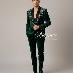 Puede incluir: Un traje de terciopelo verde oscuro con bordados florales en las solapas y a lo largo de las perneras del pantal&oacute;n. El traje tiene una solapa de sat&eacute;n negro y se combina con zapatos de vestir negros. El texto "Magnate Western Studio" es visible.