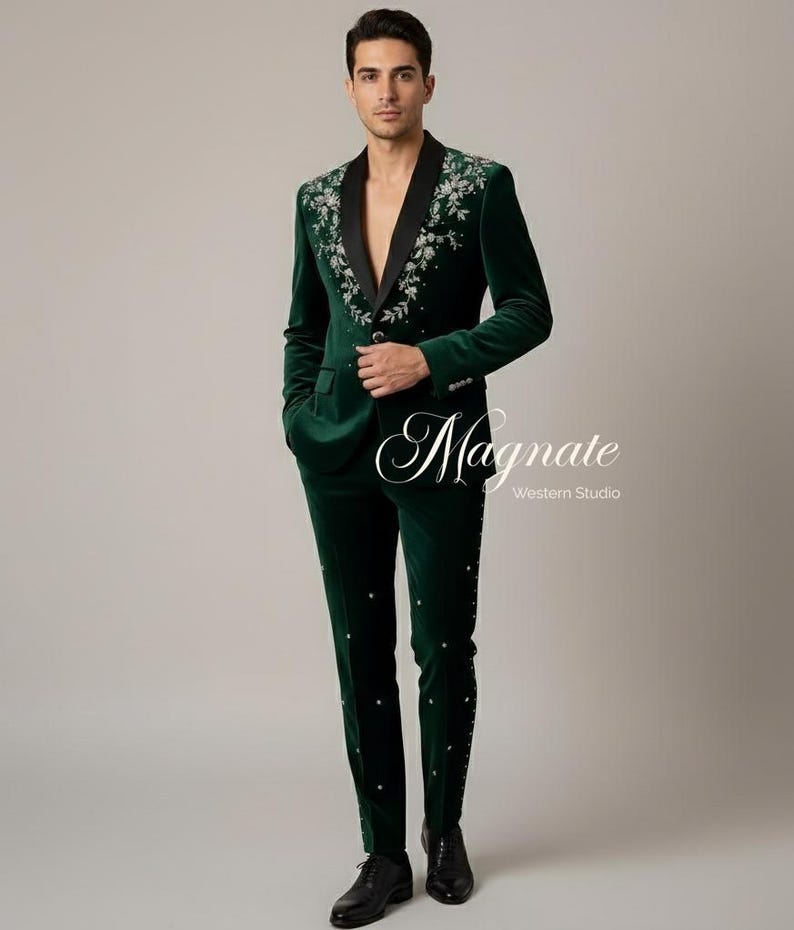 Puede incluir: Un traje de terciopelo verde oscuro con bordados florales en las solapas y a lo largo de las perneras del pantal&oacute;n. El traje tiene una solapa de sat&eacute;n negro y se combina con zapatos de vestir negros. El texto "Magnate Western Studio" es visible.