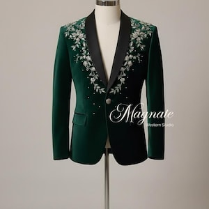 Puede incluir: Una blazer de terciopelo verde oscuro con solapa de sat&eacute;n negro, adornada con bordados florales plateados y peque&ntilde;os detalles de cristal. La chaqueta tiene un cierre de un solo bot&oacute;n y el texto "Magnate Western Studio".