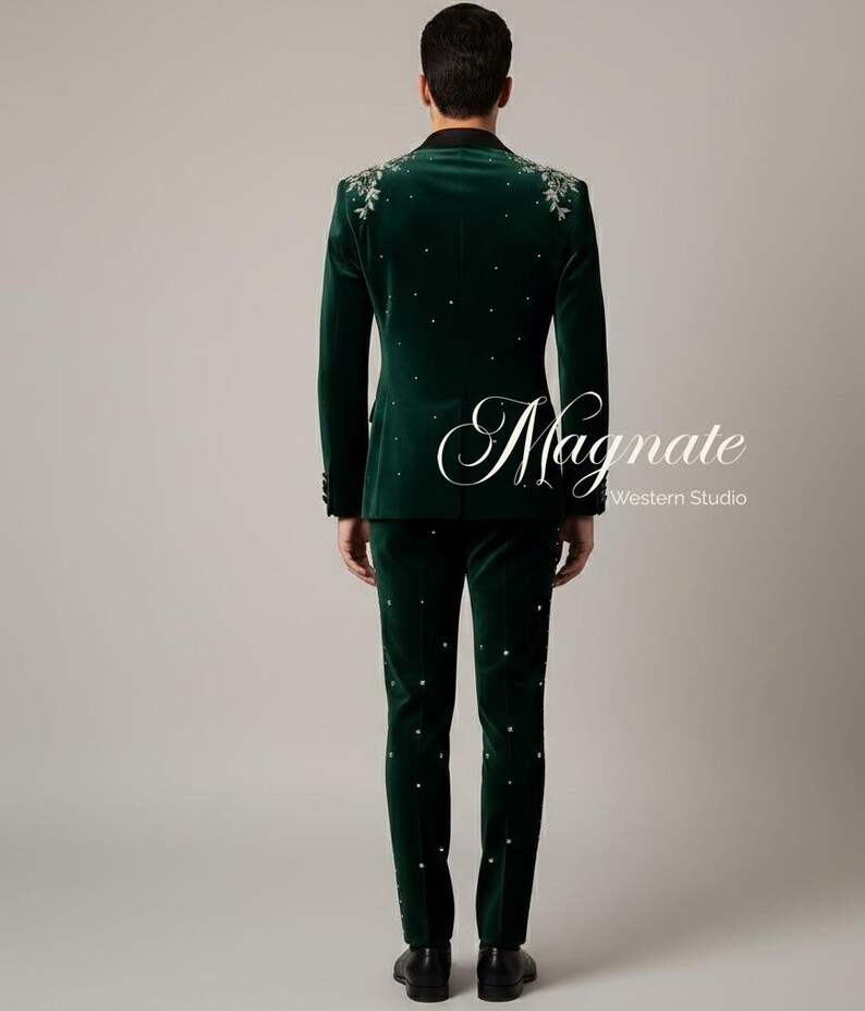 Puede incluir: Un traje de terciopelo verde oscuro con bordados florales en los hombros y adornos dispersos. El traje incluye una chaqueta y un pantal&oacute;n a juego. El texto "Magnate Western Studio" es visible en la imagen.