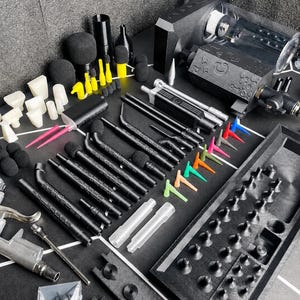 May include: A comprehensive set of black and silver automotive detailing tools including a pneumatic blow gun, various black extension wands with foam tips, colorful plastic nozzles, a black storage tray, and a white hose on a black surface.