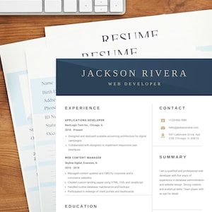 Könnte beinhalten: Ein Lebenslauf für Jackson Rivera, einen Webentwickler, liegt auf einem Holztisch. Der Lebenslauf enthält Berufserfahrung, Kontaktinformationen, eine Zusammenfassung und Fähigkeiten. Eine Tastatur, Büroklammern und dekorative Papierhalter sind ebenfalls sichtbar.