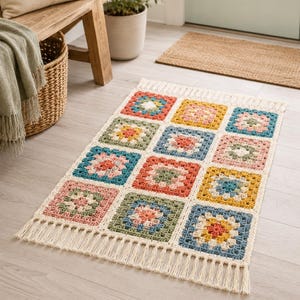 Peut inclure: Un tapis rectangulaire au crochet composé d'une grille de douze carrés granny colorés dans des tons terre cuite, jaune moutarde, vert sauge et rose poudré, bordé de fil crème et terminé par de longues franges couleur crème aux deux extrémités.
