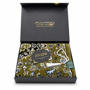 Pode incluir: Uma caixa de presente preta contendo um tapete de oração verde-oliva com padrão floral, um colar de oração branco com borla e um pequeno cartão preto com texto dourado que diz "So remember me; I will remember you. Quran 2:152."
