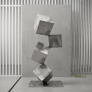 Pode incluir: Uma escultura vertical composta por quatro cubos de metal prateado escovado empilhados numa formação equilibrada e escalonada. Os cubos estão ligados pelos cantos, elevando-se a partir de uma base metálica quadrada e plana com acabamento.