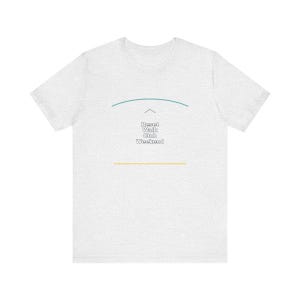 May include: A light gray heathered short-sleeve t-shirt featuring a graphic design on the chest. The design includes a teal curved line above the text Reset Walk Club Weekend in white letters, with a thin yellow horizontal line below the text.