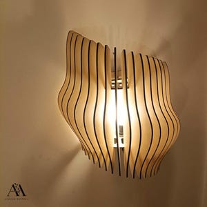 May include: A wooden wall sconce with a unique, wavy design. The light fixture is made of light-colored wood with vertical black lines, creating a layered effect. The light shines through the wooden slats.