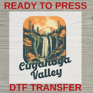 May include: A DTF transfer sheet featuring a graphic of a waterfall cascading over rocks surrounded by orange and dark green trees under a sunset sky. The text "READY TO PRESS" appears at the top, and "Cuyahoga Valley" is printed in dark blue below.