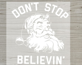 May include: White DTF transfer with a Santa Claus illustration and the text "DON'T STOP BELIEVIN'". The words "READY TO PRESS" and "DTF TRANSFER" are in red. The Santa illustration is smiling.
