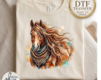 May include: A cream-colored t-shirt featuring a watercolor-style illustration of a brown horse with a flowing mane adorned with beads and feathers. The horse wears a patterned bandana in shades of orange, blue, and black. Text reads HIGH QUALITY DTF TRANSFER.