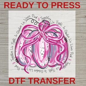 May include: A heat transfer design featuring a stylized pumpkin in shades of pink, white, and grey, wrapped in a pink awareness ribbon. The text reads: Ready to Press, DTF Transfer, and In October We Wear Pink Together We Fight.