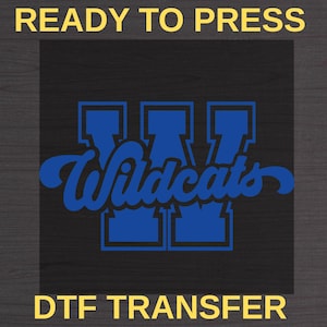 Peut inclure: Transfert DTF avec le logo des Wildcats, prêt à presser. Le motif présente le mot "Wildcats" en écriture cursive sur un logo "W" bleu sur fond noir. Les mots "READY TO PRESS" et "DTF TRANSFER" sont en jaune.