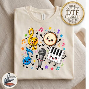 May include: A cream-colored t-shirt featuring a colorful graphic of cartoon musical instruments and notes with smiling faces, including a treble clef, tambourine, microphone, piano keyboard, and blue eighth note, surrounded by small stars.