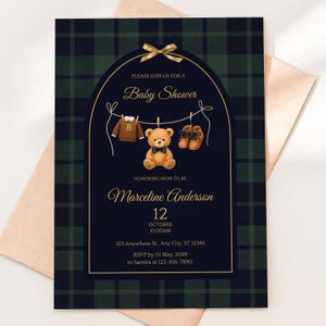 May include: Baby shower invitation with a navy blue and green plaid pattern. The design includes a teddy bear, baby clothes, and shoes suspended on a clothesline. The text reads "Please join us for a Baby Shower" and includes the honoree's name, date, time, and RSVP details.