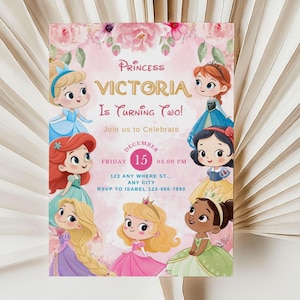 May include: A princess-themed birthday invitation featuring cartoon illustrations of princesses. The invitation reads "Princess Victoria Is Turning Two!" with event details including the date, time, and RSVP information. The design includes floral accents.