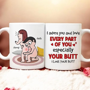以下が含まれることがあります： 2つの白いセラミックマグカップ。1つのマグカップには、「Jenny」と「Jack」という名前の漫画のカップルが描かれています。もう1つのマグカップには、「I adore you and love EVERY PART OF YOU especially YOUR BUTT I LOVE YOUR BUTT」というテキストが赤と黒で書かれています。