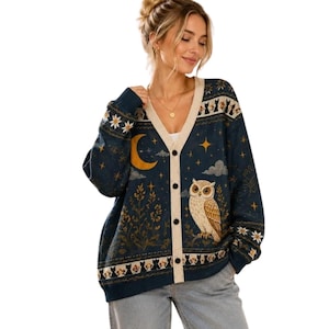 May include: A navy blue V-neck cardigan featuring a cream-colored button placket. The knit fabric displays a pattern of a yellow crescent moon, stars, clouds, floral motifs, and a brown owl, with a border of black cat silhouettes.