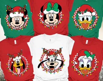 May include: A collection of six t-shirts in red, green, and white, each featuring a DTF transfer of a Disney character wearing a Christmas hat. The characters include Mickey, Minnie, Donald, Pluto, Goofy, and Daisy, all framed by a checkered circle and colorful holiday lights. The text Ready to press DTF Transfer is printed at the top.