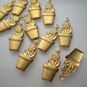 May include: A collection of 12 gold-toned metal charms shaped like flower pots with a single flower growing out of each pot. The charms are perfect for adding a touch of whimsy to jewelry or crafts.