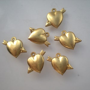 May include: Six gold-coloured heart charms with an arrow through them. The charms are ideal for jewellery making or crafting.