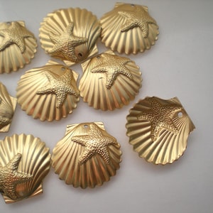 May include: A collection of gold-colored seashell charms, each featuring a starfish design. The charms have a textured surface and a small hole for stringing. These decorative charms are ideal for jewelry making or craft projects.